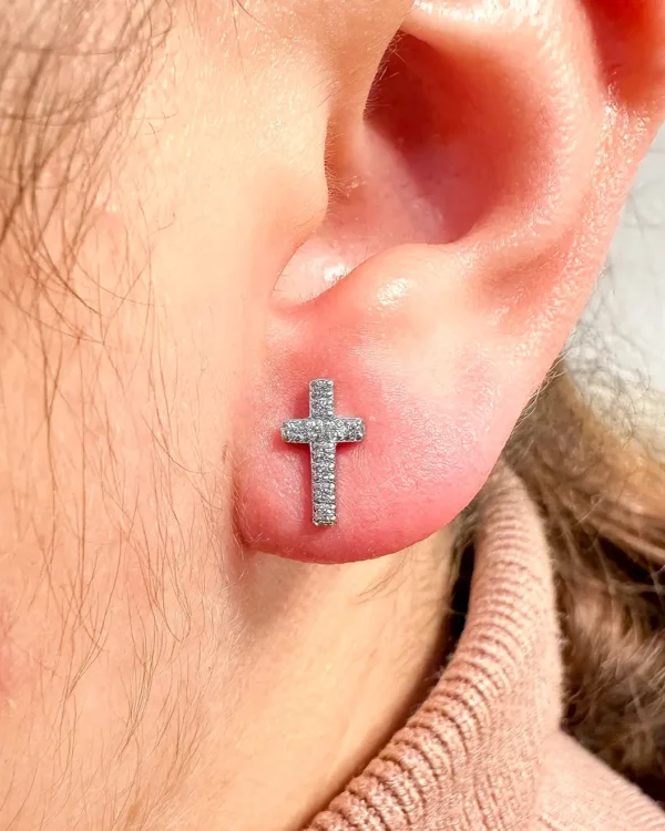 Holy cross stud earrings with stones displayed in jewelry box at sunset in Malta