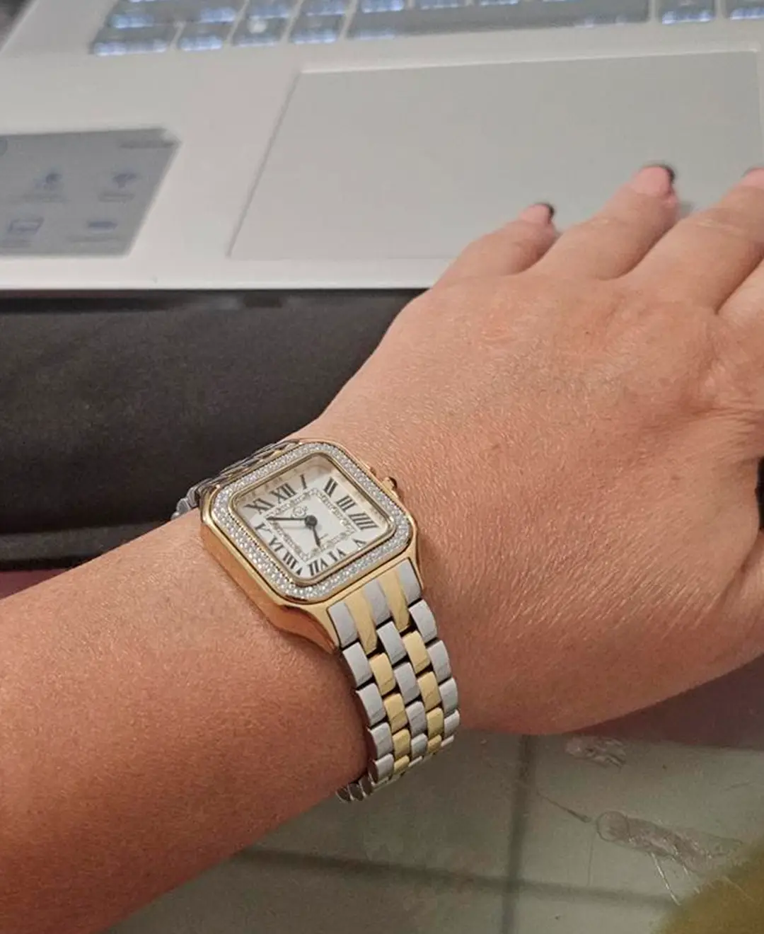 Women's GV2 Bellagio two-tone diamond watch worn on wrist near laptop